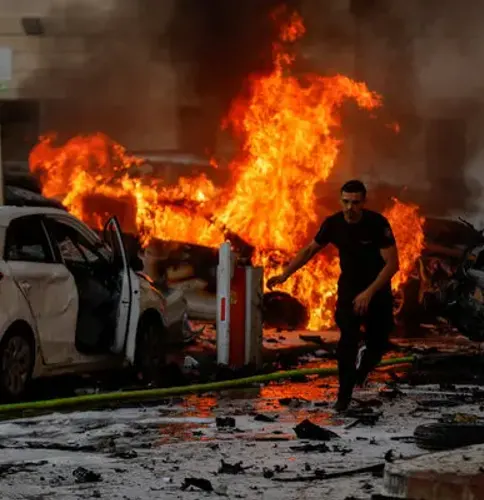 אדם רץ ברחוב זרוע שברים, על פני מכוניות בוערות ולהבות גבוהות