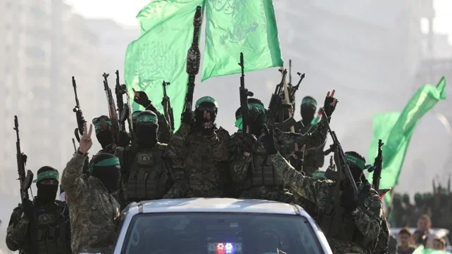 Masked gunmen in green headbands raise rifles and green Hamas flags while riding on a vehicle in a parade