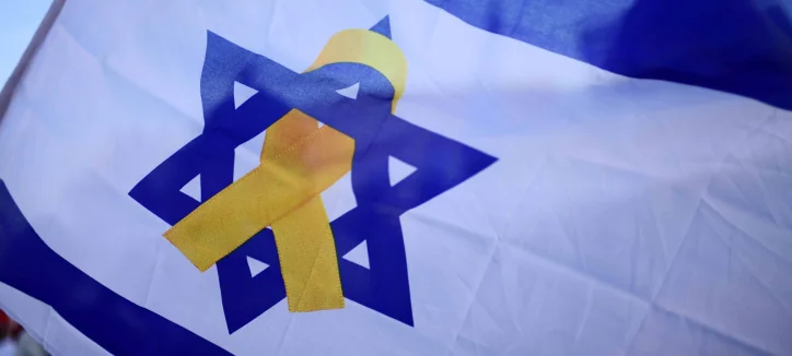 A waving Israeli flag with a yellow ribbon placed over the Star of David
