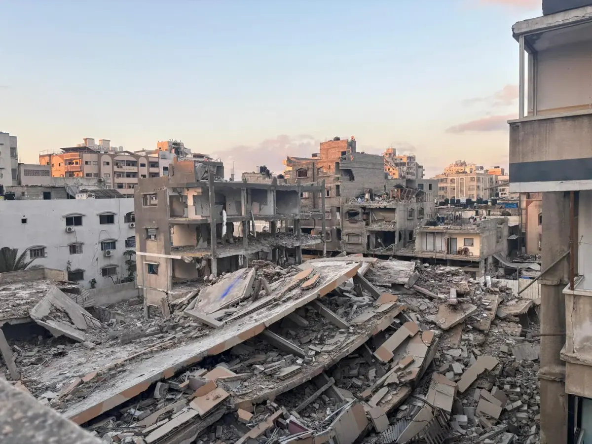 Collapsed multi-story buildings and heaps of rubble in a dense urban neighborhood at dusk